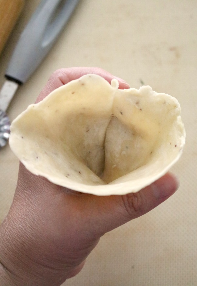an image showing how to create the dough cone shape to fill for potato samosas.