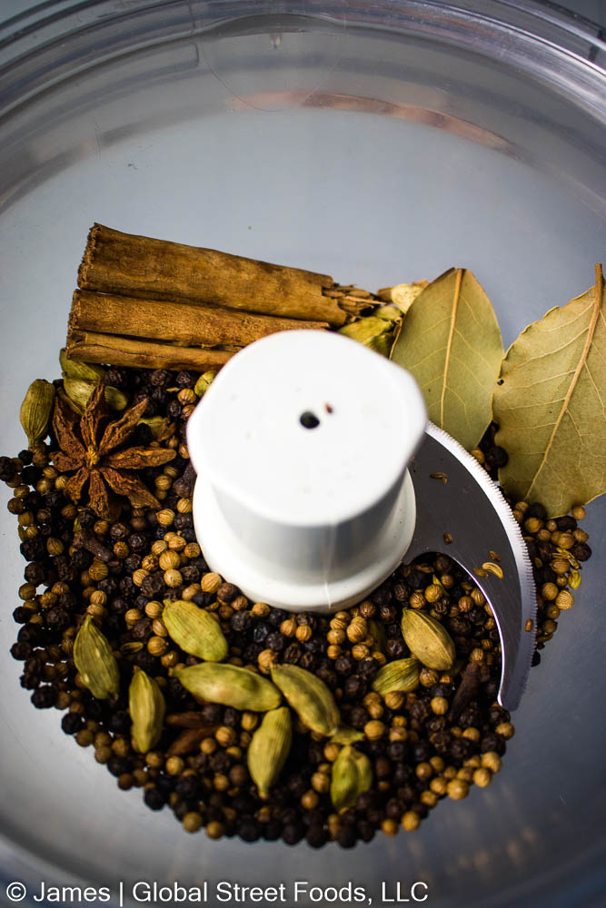 A food processor bowl filled with the garam masala spices to be ground into a powder.